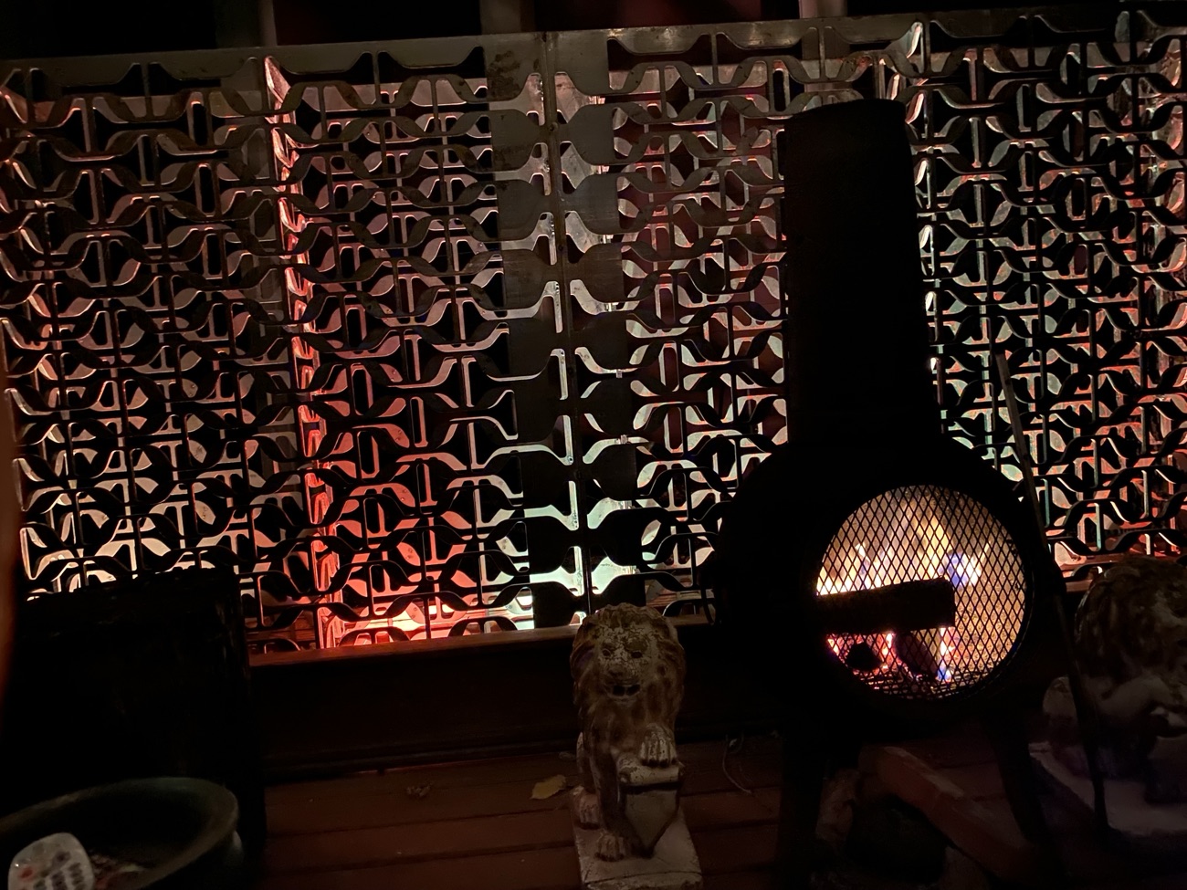 Custom salvaged-metal screen wall backlit by fire at night